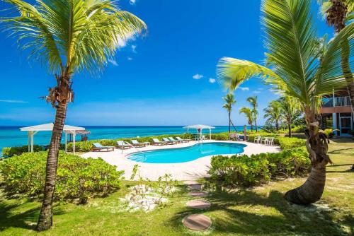 a resort swimming pool with palm trees and the ocean at Northern Lights #4 Condo in Old Man Bay