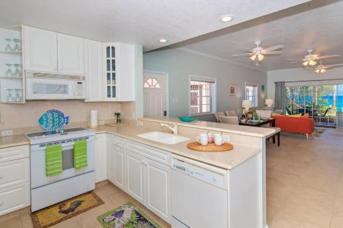 a kitchen with white cabinets and a living room at Northern Lights #4 Condo in Old Man Bay