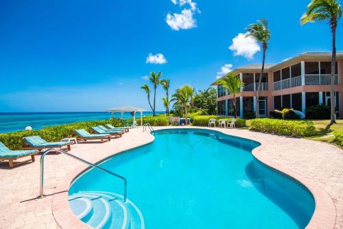 a resort swimming pool with lounge chairs and the ocean at Northern Lights #4 Condo in Old Man Bay