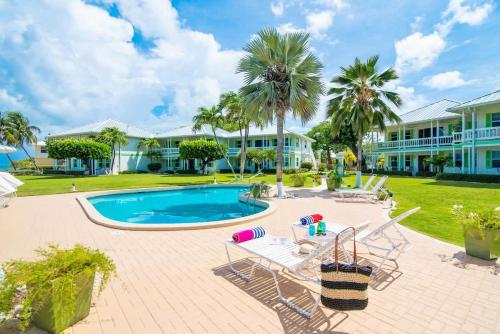 a resort with a swimming pool and palm trees at Cocoplum #1 Condo in George Town