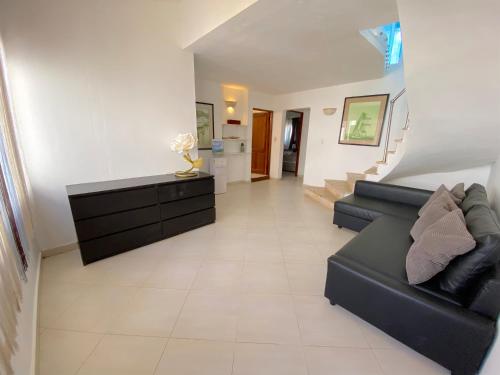 a living room with a black couch and stairs at LOS CORALES Resort VILLAS & Apartments WIFI BEACH Club & SPA in Punta Cana