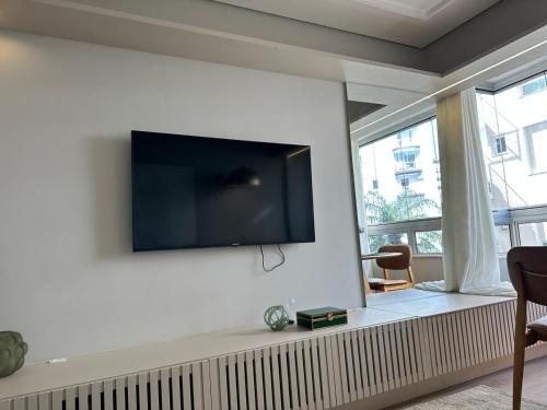 a living room with a flat screen tv on the wall at Refúgio Sofisticado Beira Mar in Florianópolis
