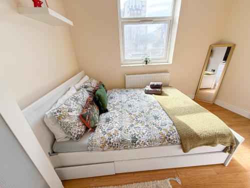 a bed in a small room with a window at Bright 3-Bedroom Aldgate Flat with Free WIFI near Tower Hill, Brick Lane & Spitalfields in London