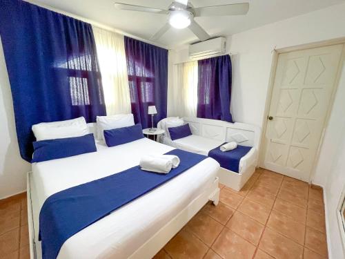 a bedroom with two white beds and blue curtains at LOS CORALES Resort VILLAS & Apartments WIFI BEACH Club & SPA in Punta Cana