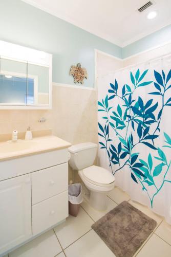 a bathroom with a toilet and a shower curtain with leaves at Northern Lights #6 Condo in Old Man Bay