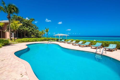a pool with chairs and the ocean in the background at Northern Lights #6 Condo in Old Man Bay