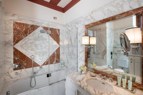 a bathroom with a tub and a sink and a mirror at Helvetia&Bristol Firenze – Starhotels Collezione in Florence