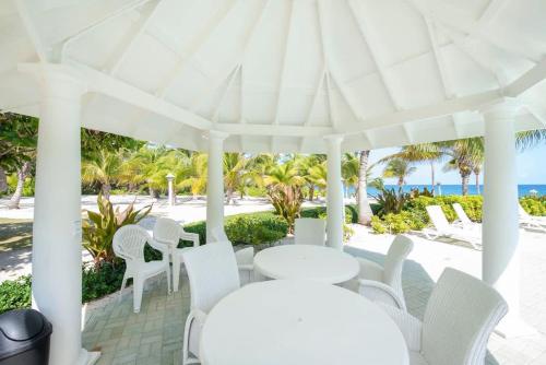 a white pavilion with white chairs and tables and the beach at On the Bay #103 Condo in Old Man Bay