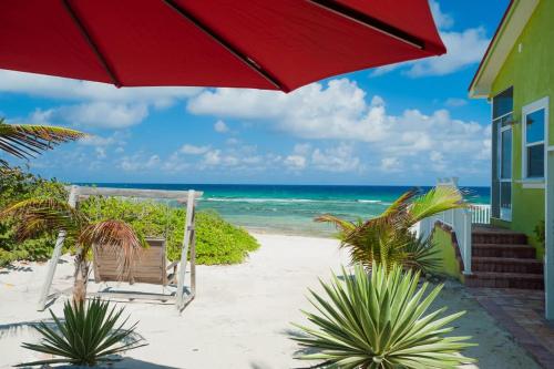 a red umbrella and a chair on the beach at Parrot-ise 4 Bedroom Villa in Brinkleys