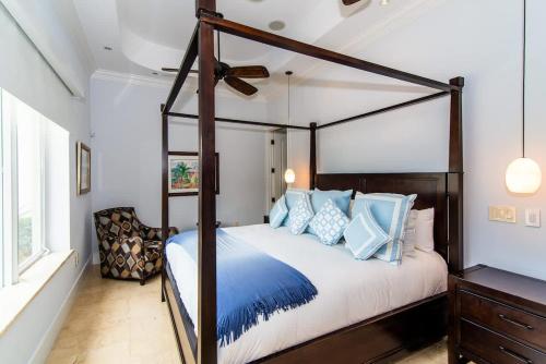 a bedroom with a canopy bed with blue pillows at Faroway Luxury Villa in Half Way Pond
