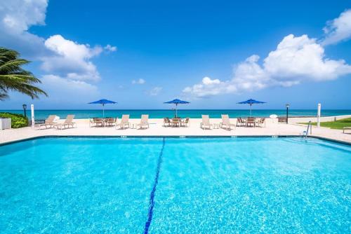 a swimming pool with chairs and umbrellas and the ocean at Georgetown Villas #201 in George Town