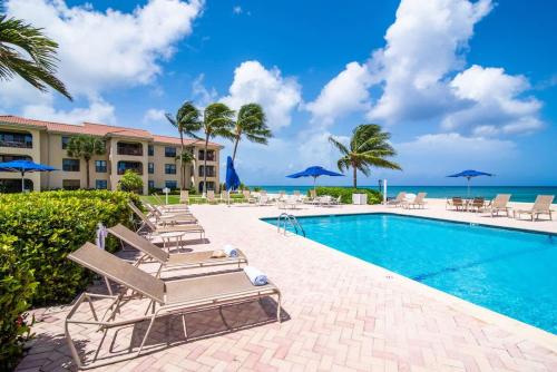 a resort swimming pool with lounge chairs and the ocean at Georgetown Villas #201 in George Town