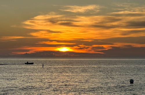 a sunset over the ocean with a boat in the water at Georgetown Villas #201 in George Town