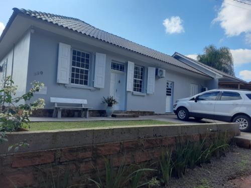 a white house with a car parked in front of it at Casa Finger á 800m do Núcleo de casas Enxaimel da Adoma e do Centro in Ivoti