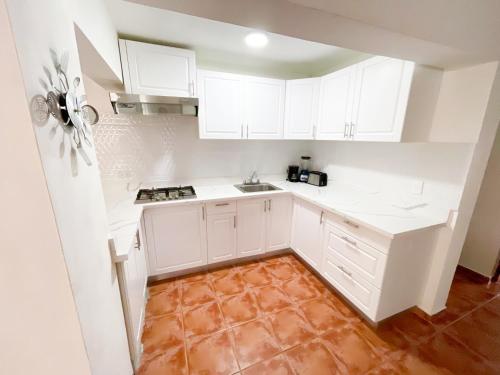 a white kitchen with white cabinets and a tile floor at LOS CORALES Resort VILLAS & Apartments WIFI BEACH Club & SPA in Punta Cana