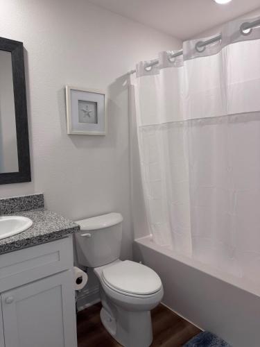 a white bathroom with a toilet and a sink at Chic Beach Home Near Airport Casino Base in Gulfport