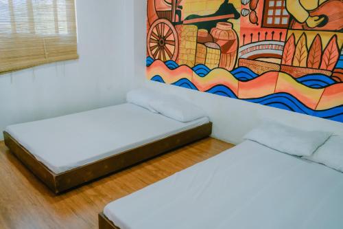 two beds in a room with a painting on the wall at The Bistro House - Loft Unit - Vigan in Vigan