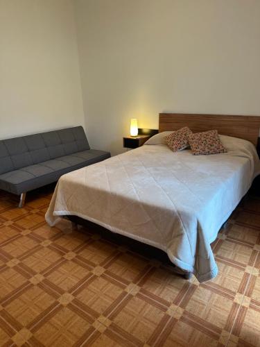a bedroom with a large bed and a couch at Casita Garden Junquillos in El Palomar