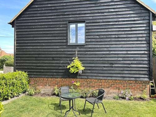 two chairs and a table in front of a house at Charming King Bed Ensuite Studio in Peaceful West Challow in Wantage