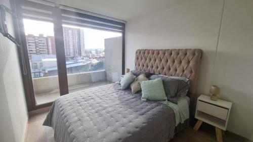 a bedroom with a large bed with a large window at Comodidad y ubicación perfecta in Temuco