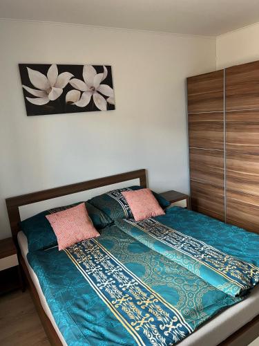 a bedroom with a bed with blue sheets and pink pillows at Apartmán Losonci in Nesvady
