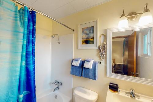 a bathroom with a blue shower curtain and a toilet at Lamplighter Inn Group Stay 2 in Bandon