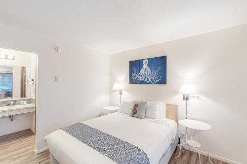 a white bedroom with a bed and two tables at Lamplighter Inn Group Stay 1 in Bandon