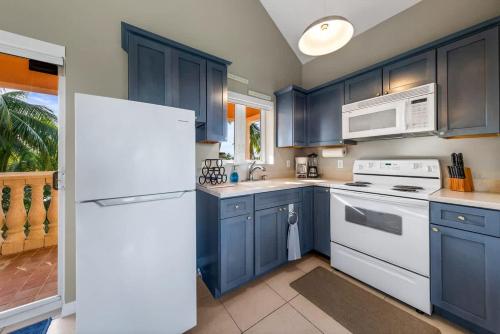 a kitchen with blue cabinets and a white refrigerator at Pieces of Eight LUXE 6BR in Driftwood Village