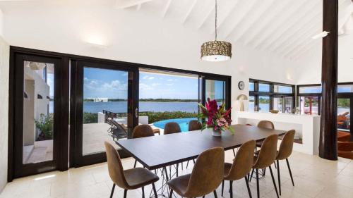 a dining room with a table and chairs with a view of the ocean at Songbird 4 BR Anguilla Villa in The Valley
