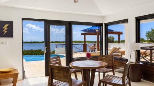 a dining room with a table and a view of the ocean at Songbird 4 BR Anguilla Villa in The Valley
