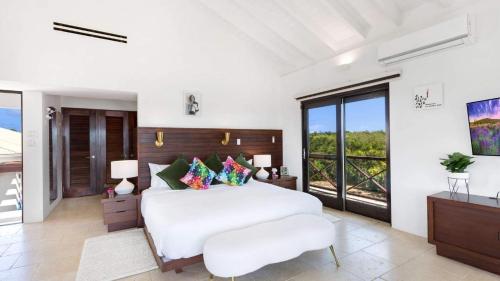 a bedroom with a white bed and a large window at Songbird 4 BR Anguilla Villa in The Valley