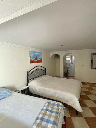 a bedroom with two beds and a checkered floor at Au soleil couchant in Mirleft