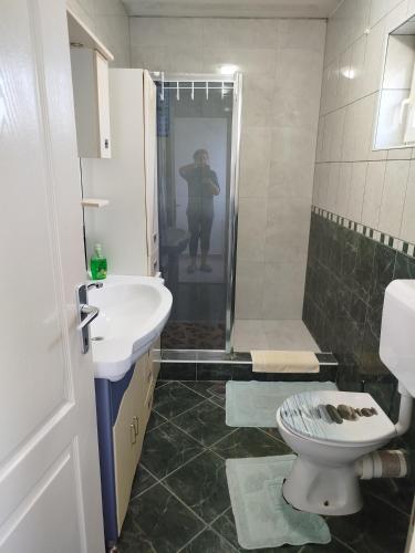 a person taking a picture of a bathroom with a toilet and sink at Apartman Ivana in Slavonski Brod
