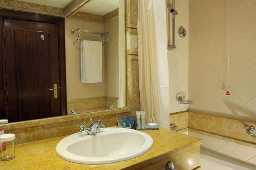 un bagno con un lavandino, uno specchio e una vasca di Pestana Royal All Inclusive Ocean & Spa Resort a Funchal
