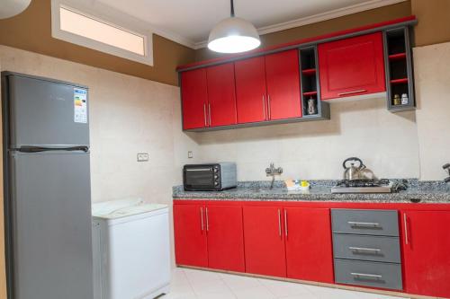 a kitchen with red cabinets and a white refrigerator at Appart hotel tanger in Dakhla