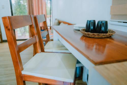 a dining room table with a wooden chair and a table with dishes at The River House - Govantes Guesthouse in Vigan