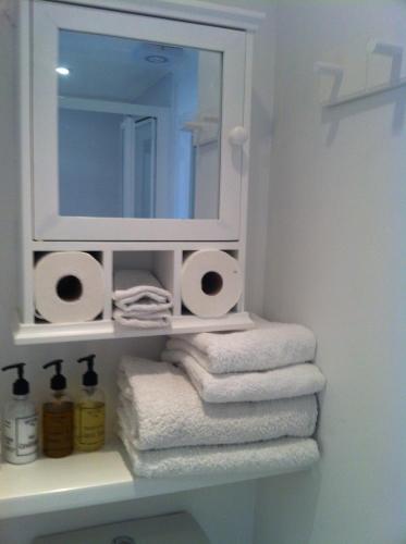 a bathroom with a mirror and towels on a shelf at Trelawney Guest House Room only in Falmouth