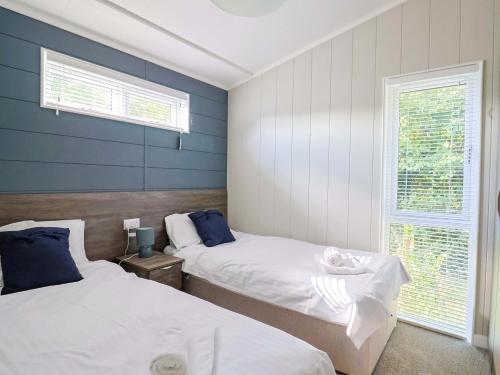 Dos camas en una habitación con paredes azules y blancas. en Cedar 1, en Lyme Regis