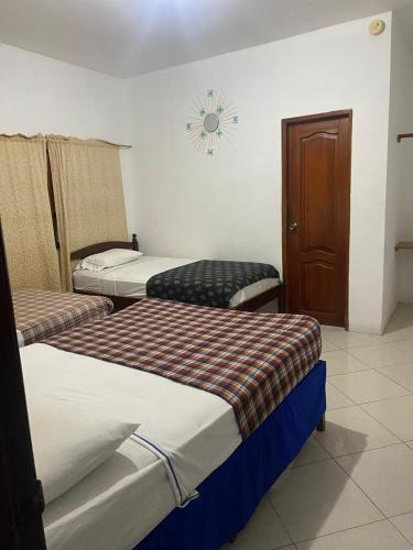 a room with three beds and a clock on the wall at Hotel Mar Adentro - Salinas in Salinas