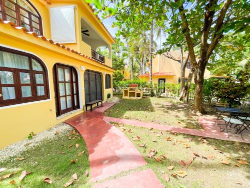 a yellow house with a walkway next to a yard at LOS CORALES Resort VILLAS & Apartments WIFI BEACH Club & SPA in Punta Cana