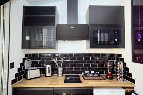 a kitchen with black and white tile on the wall at Romance House in Arnouville-lès-Gonesse