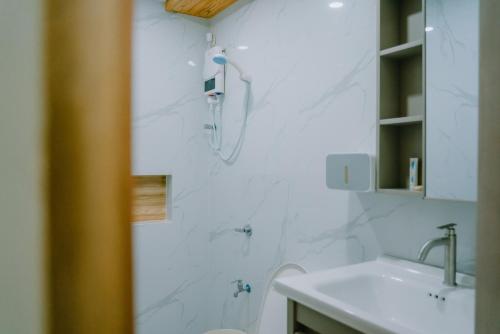 a white bathroom with a shower and a sink at The Tree House - Connecting Loft Units Govantes in Vigan
