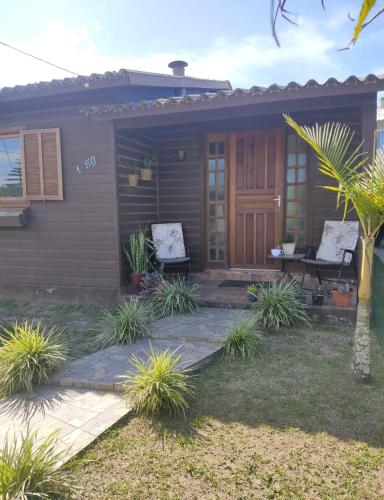 a small house with two chairs and a patio at Pousada Albino Goedert in Passo De Torres