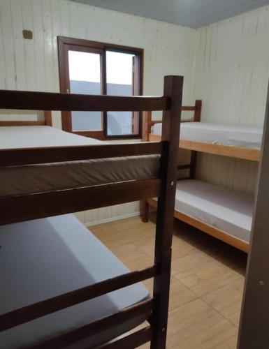 a room with three bunk beds and a window at Pousada Albino Goedert in Passo De Torres