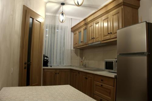 a kitchen with wooden cabinets and a refrigerator at Király Apartments in Praid
