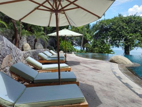 a row of lounge chairs with an umbrella next to a pool at Tokipa at Punta Sayulita in Sayulita