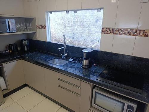 a kitchen counter with a sink and a window at casa para Oktoberfest in Blumenau