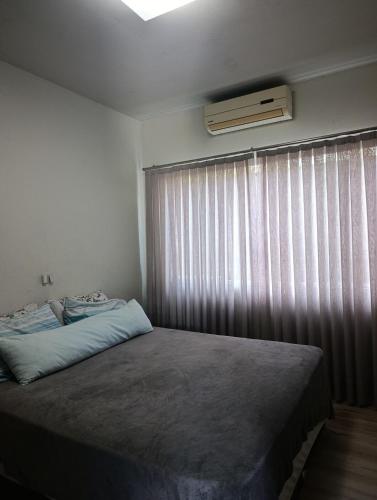 a bedroom with a bed and a window with curtains at casa para Oktoberfest in Blumenau