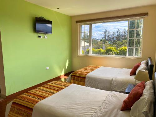 a room with two beds and a flat screen tv at Las Hortensia's Casa De Huespedes in Tababela