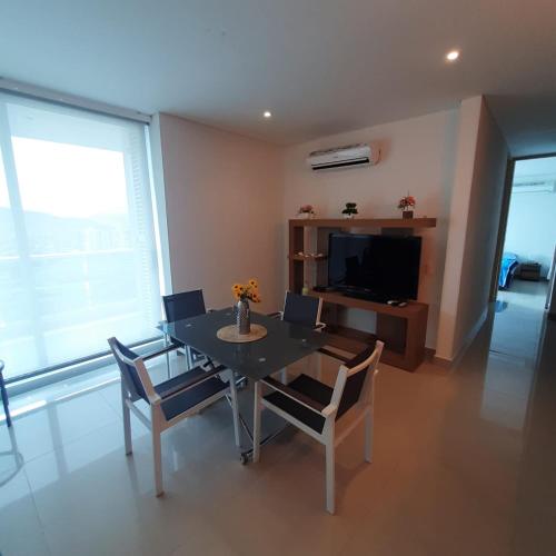 a dining room with a table and chairs and a television at Reserva Del Mar Apartamentos in Gaira